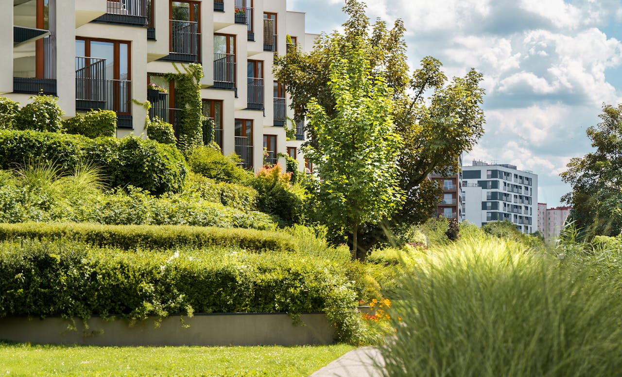 home-services-03 Elegant modern residential complex with lush gardens and urban landscape views.
