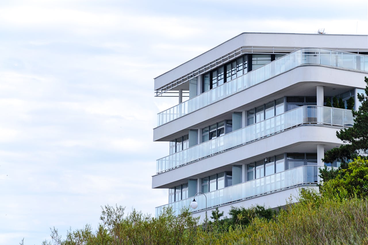 home-services-004 A contemporary apartment building with glass balconies and sleek design set against a clear sky.